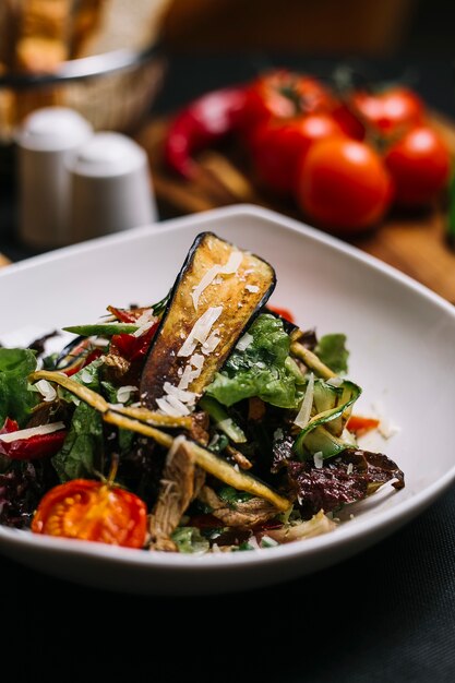 Vista laterale dell'insalata di manzo con aglio grigliato peperoni di avocado e pomodorini pormesan in una ciotola