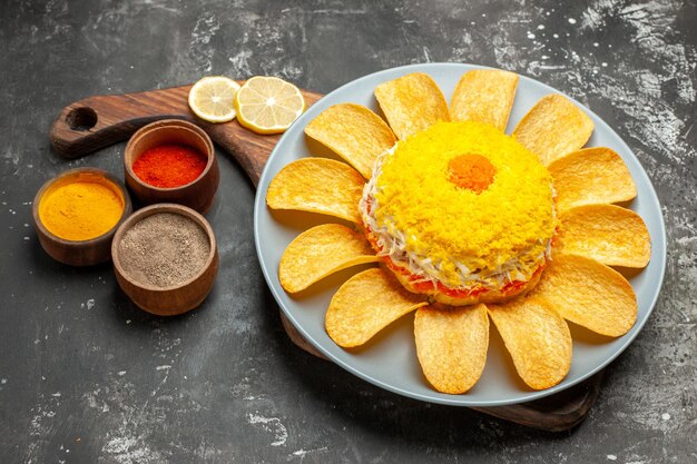 Vista laterale dell'insalata sul supporto del piatto con limone ed erbe aromatiche sul lato sul tavolo grigio scuro