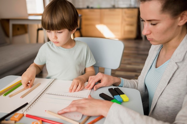 Vista laterale dell'insegnante femminile che insegna al bambino a casa