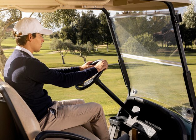 Vista laterale dell'uomo alla guida di golf cart