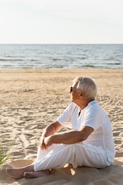 Vista laterale dell'uomo anziano che gode del suo tempo in spiaggia