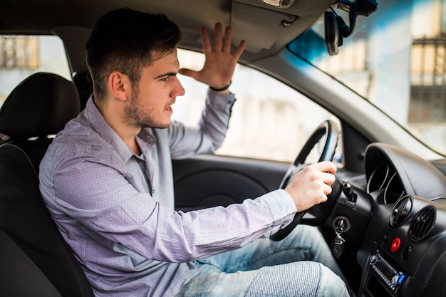 Vista laterale dell'uomo arrabbiato in abbigliamento casual alla guida di auto