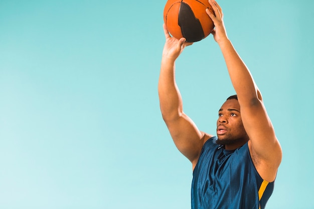 Vista laterale dell'uomo atletico che gioca a basket con lo spazio della copia