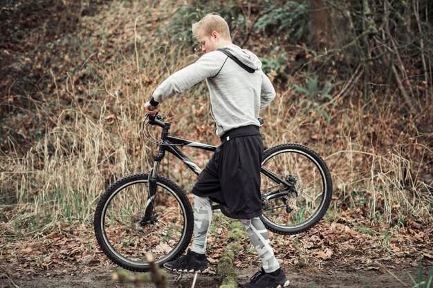 Vista laterale dell&#39;uomo che cammina con la sua bicicletta