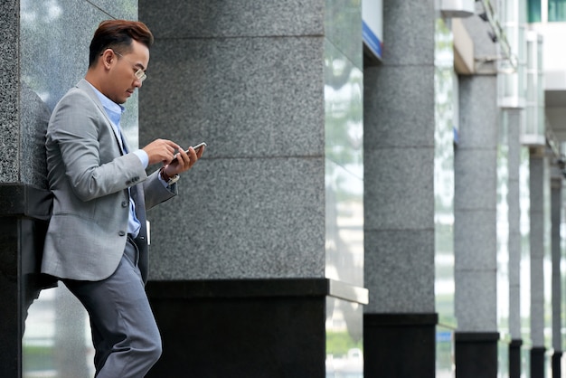 Vista laterale dell'uomo che controlla smartphone all'intervallo di pranzo all'aperto