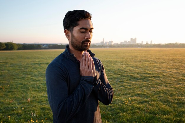 Vista laterale dell'uomo che fa yoga all'aperto