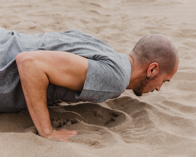 Vista laterale dell'uomo che fa yoga sulla sabbia