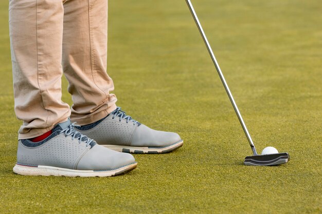 Vista laterale dell'uomo che gioca a golf con il club e la palla