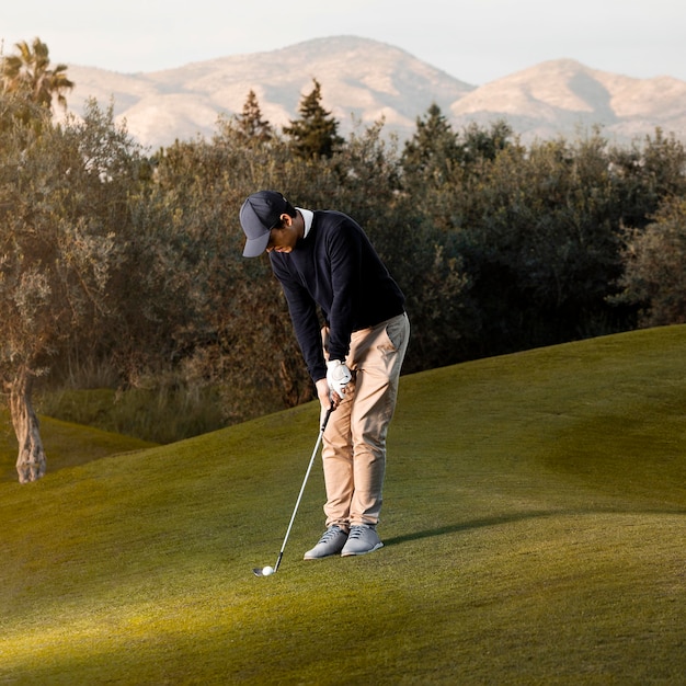 Vista laterale dell'uomo che gioca sul campo da golf erboso