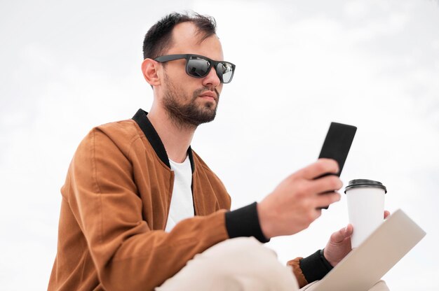 Vista laterale dell'uomo che lavora al computer portatile mentre si mangia il caffè