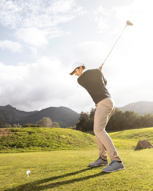 Vista laterale dell'uomo che pratica il golf sul campo