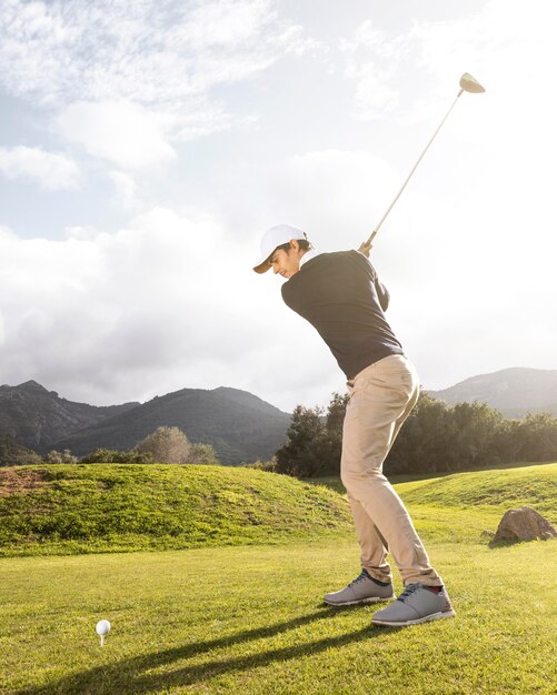 Vista laterale dell'uomo che pratica il golf sul campo