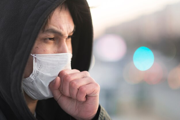 Vista laterale dell'uomo che tossisce nella mascherina medica