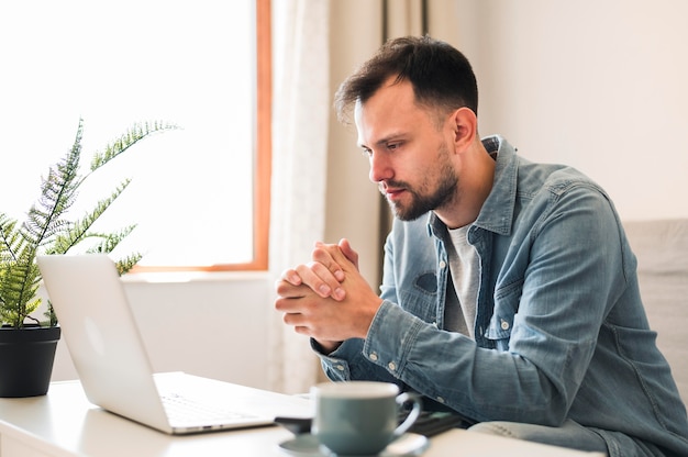 Vista laterale dell'uomo che wotking al suo computer portatile