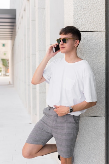 Vista laterale dell'uomo con gli occhiali da sole parlando al telefono all'aperto