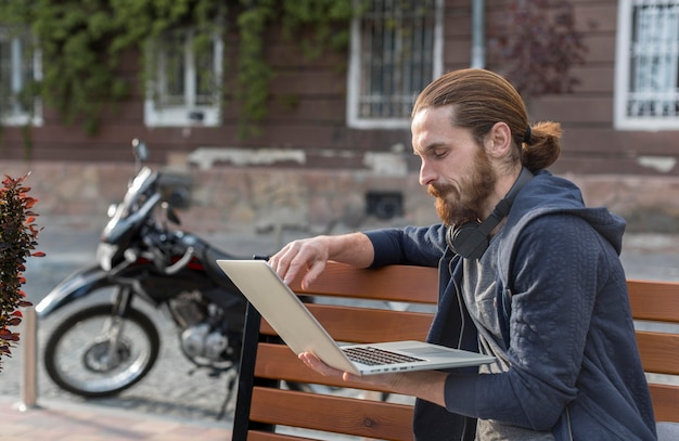 Vista laterale dell'uomo con il computer portatile in città