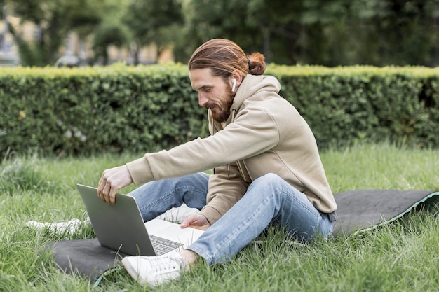 Vista laterale dell'uomo con il computer portatile in parco