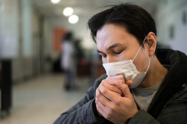 Vista laterale dell'uomo con la tosse della mascherina medica