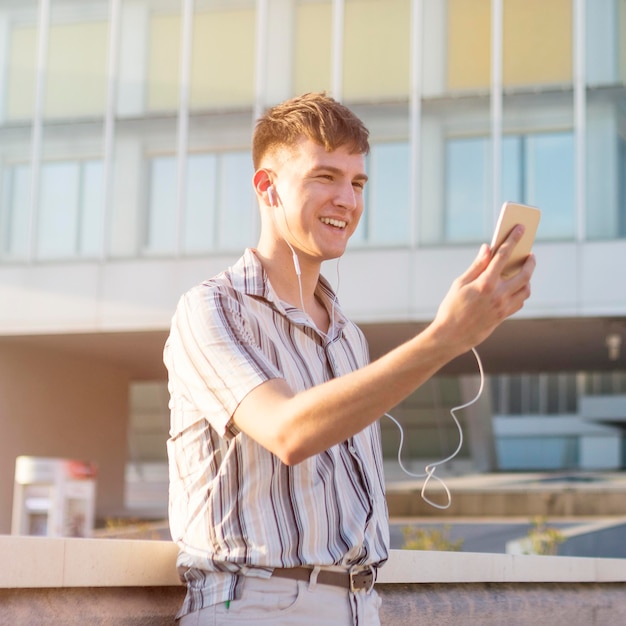 Vista laterale dell'uomo di smiley che ha una videochiamata all'aperto