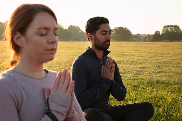 Vista laterale dell'uomo e della donna che meditano all'aperto