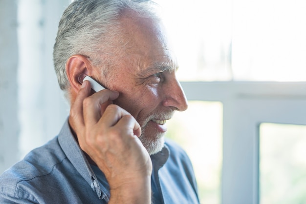 Vista laterale dell&#39;uomo maggiore che comunica sulla cuffia avricolare bluetooth senza fili