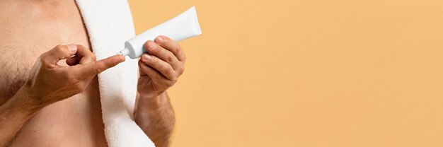 Vista laterale dell'uomo più anziano che usando crema con lo spazio della copia