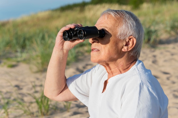 Vista laterale dell'uomo più anziano con il binocolo all'aperto