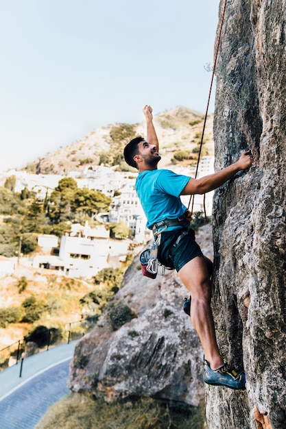 Vista laterale dell&#39;uomo sportivo che si arrampica sulla roccia