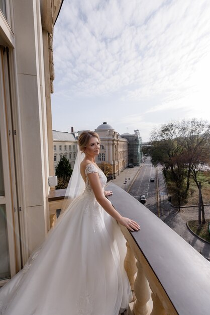 Vista laterale della bella sposa in piedi sul balcone e gode dell'aria fresca