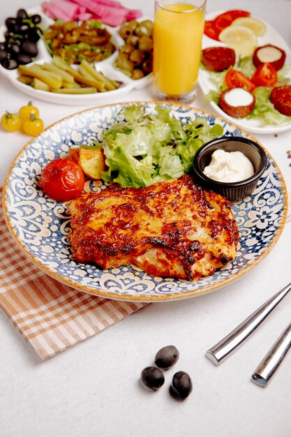 Vista laterale della carne di pollo al forno con patate e pomodori grigliati formaggio