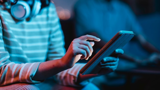 Vista laterale della donna a casa utilizzando cuffie e tablet