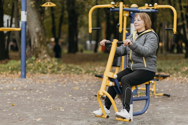 Vista laterale della donna anziana che lavora fuori all'aperto con lo spazio della copia