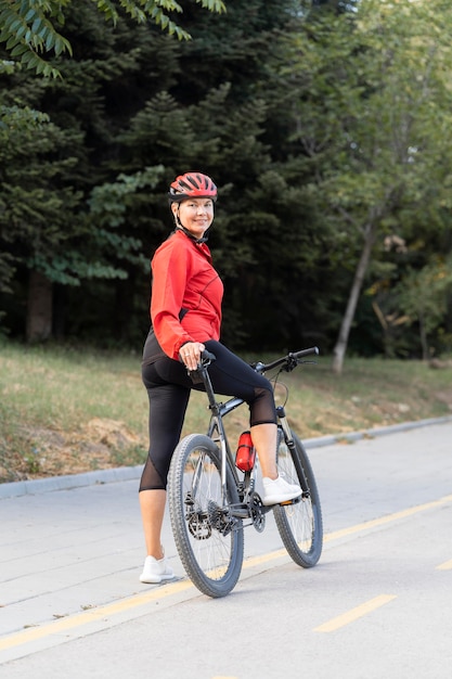 Vista laterale della donna anziana di smiley all'aperto equitazione bicicletta