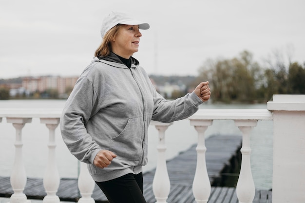 Vista laterale della donna anziana fare jogging all'aperto