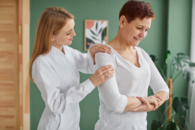 Vista laterale della donna anziana sorridente nel recupero covid facendo esercizi fisici