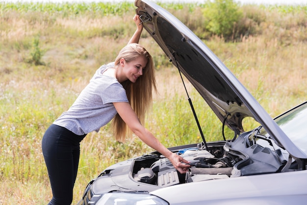 Vista laterale della donna che controlla motore sulla strada