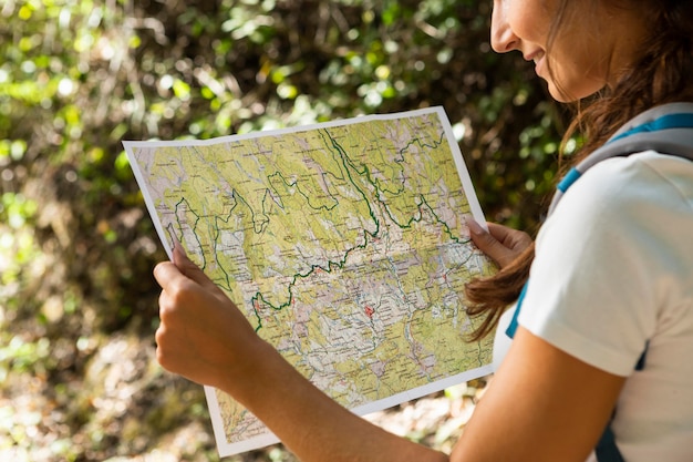 Vista laterale della donna che esplora la natura mentre guarda la mappa