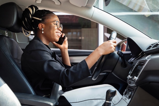 Vista laterale della donna che guida e parla sullo smartphone allo stesso tempo