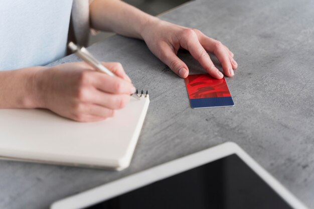 Vista laterale della donna che lavora e che scrive sul taccuino