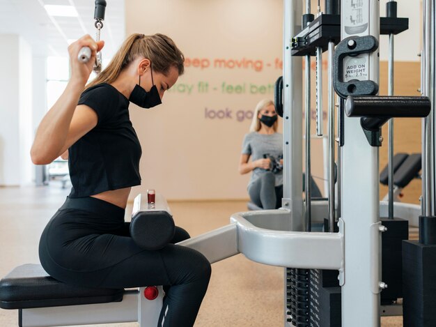 Vista laterale della donna che lavora in palestra durante la pandemia