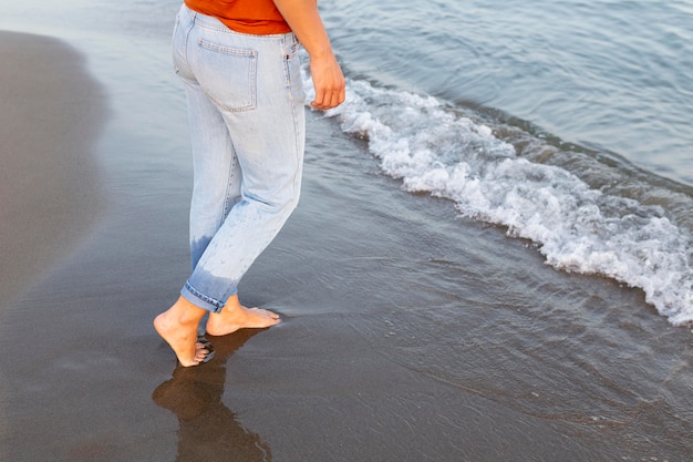 Vista laterale della donna che ottiene i suoi piedi nell'acqua alla spiaggia