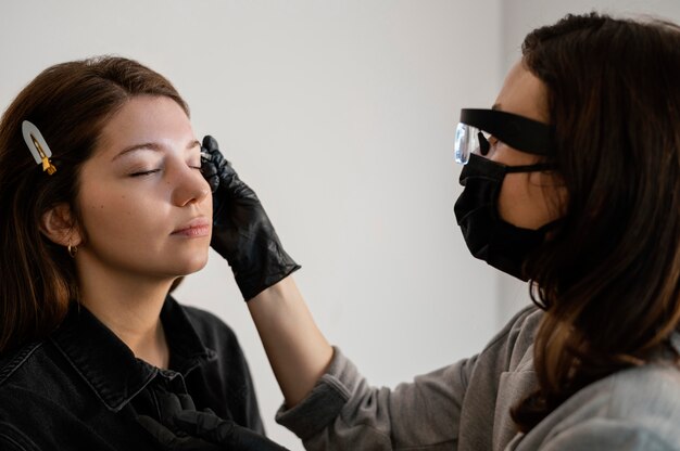 Vista laterale della donna che ottiene un trattamento per le sopracciglia dall'estetista