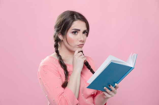 Vista laterale della donna che pensa e che tiene libro