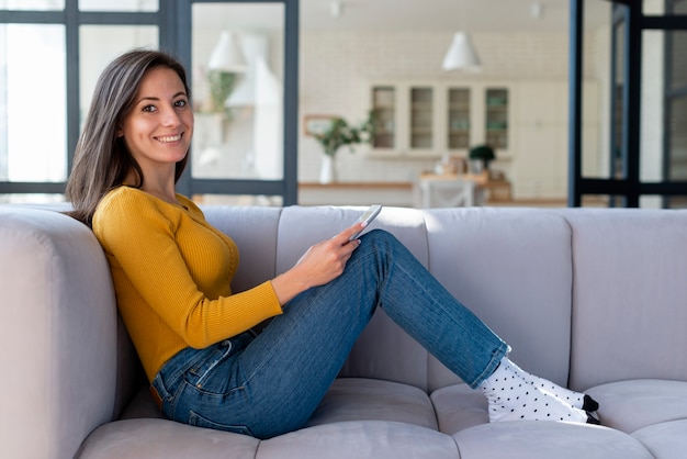 Vista laterale della donna che per mezzo della compressa sul sofà