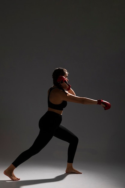 Vista laterale della donna che perfora con i guanti della scatola