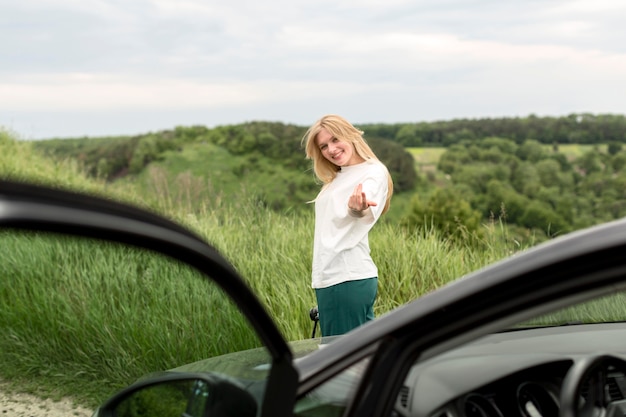 Vista laterale della donna che posa davanti all'automobile