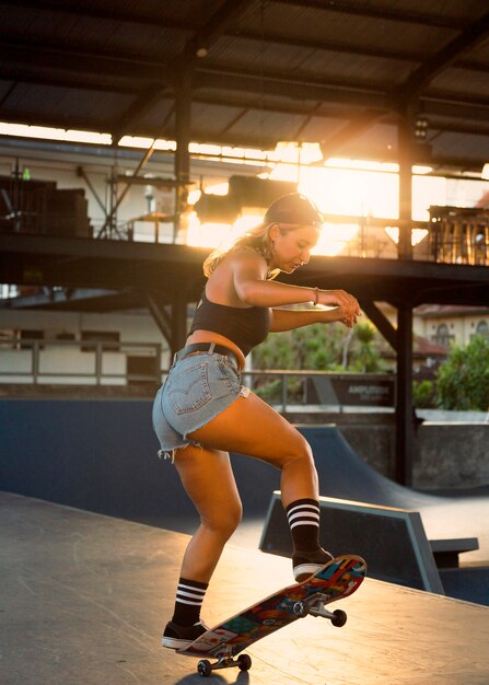 Vista laterale della donna che pratica lo skateboard