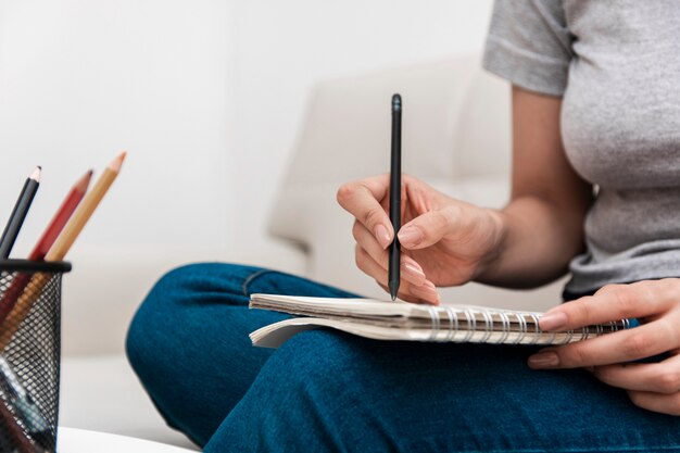 Vista laterale della donna che scrive qualcosa sul taccuino