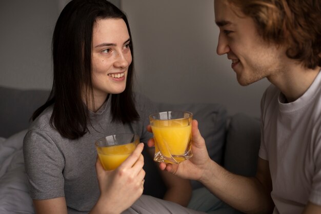 Vista laterale della donna che sorride al ragazzo mentre si tiene un bicchiere di succo d'arancia