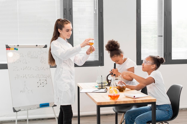 Vista laterale della donna che spiega chimica alle ragazze